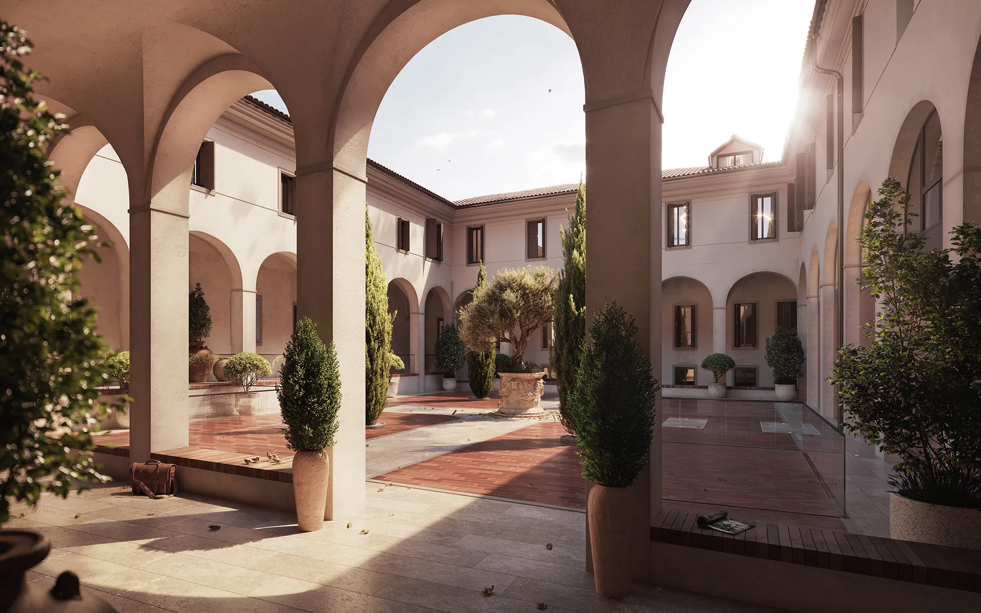 Cortile interno con archi, piante in vaso e pavimento in pietra e mattoni sotto luce solare.