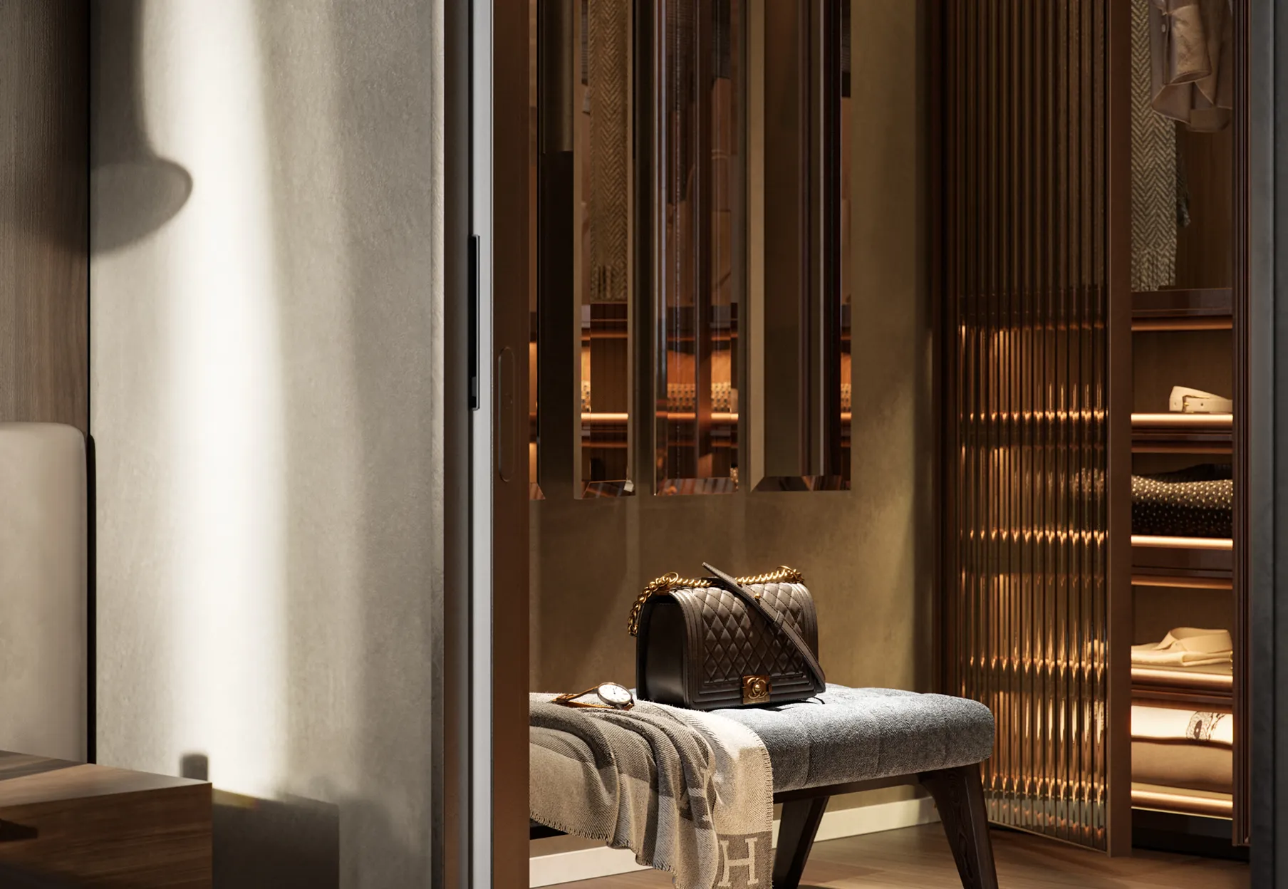 Borsa nera con tracolla e catena dorata su panca grigia con coperta, davanti a un armadio illuminato con abiti piegati.