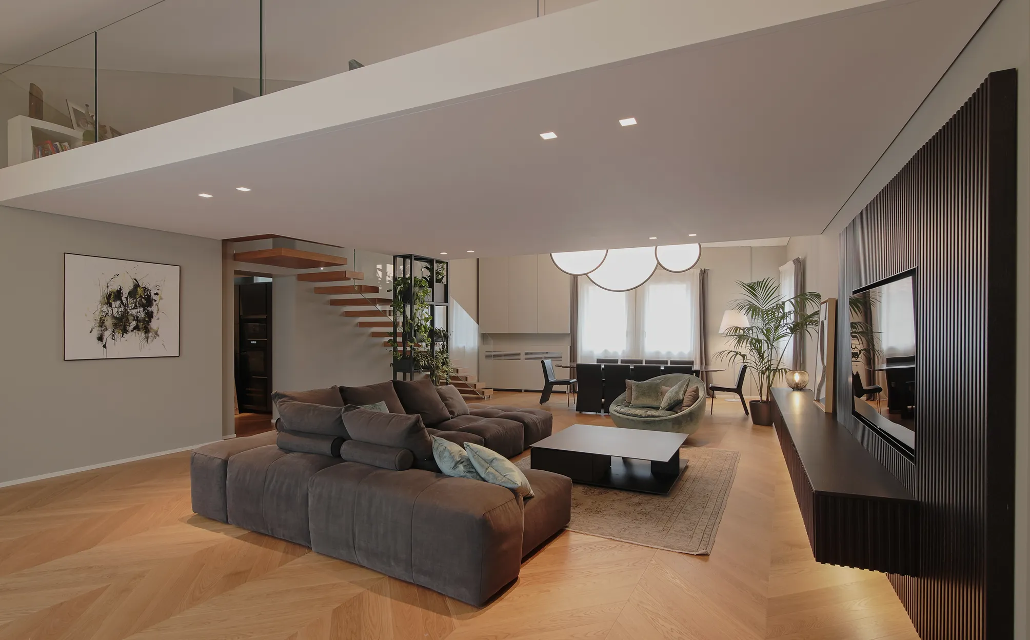 Soggiorno moderno con divano grigio, poltrona verde, tavolino nero, parete TV nera e scala a chiocciola senza ringhiera.