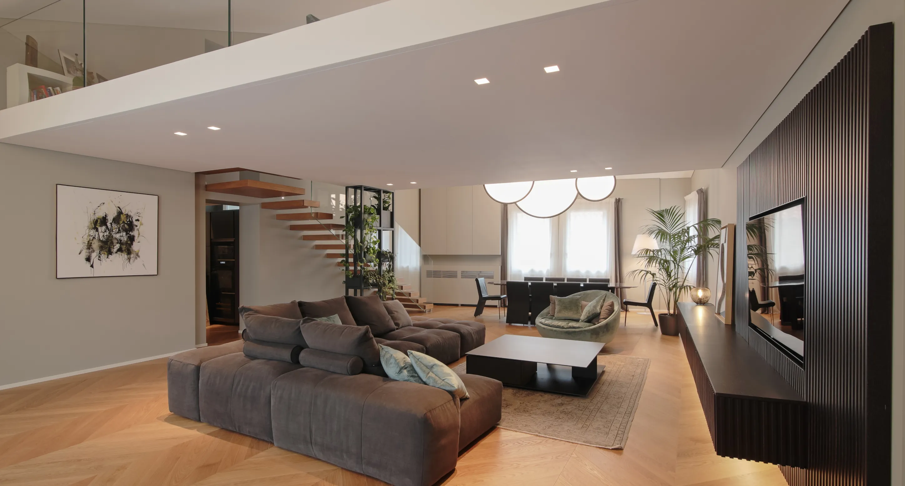 Soggiorno moderno con divano grigio, poltrona rotonda verde, tavolino nero e parete attrezzata nera con TV.