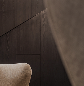 Close-up of a beige upholstered chair against a dark wooden paneled wall with angled seams.